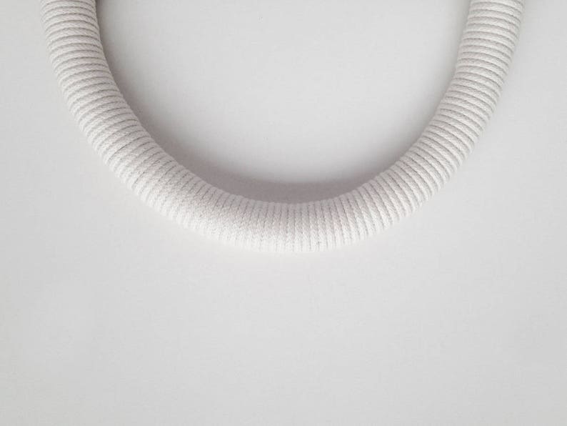 May include: A white, braided rope in the shape of a circle.