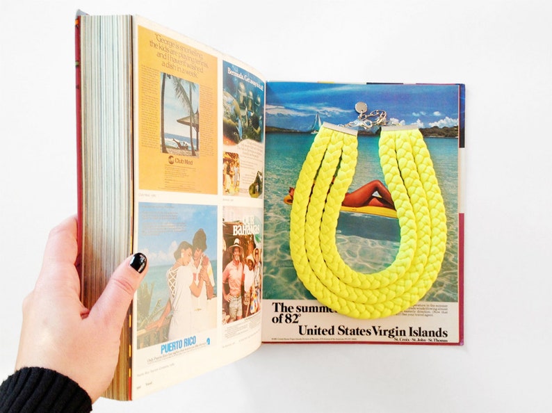 May include: A bright yellow braided necklace on a magazine page with a tropical beach scene and the text "The summer of '82 United States Virgin Islands".