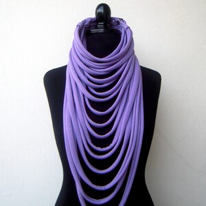 May include: A long, layered purple scarf made of fabric. The scarf is draped around a black mannequin.