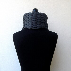 May include: A grey knitted infinity scarf on a black mannequin.