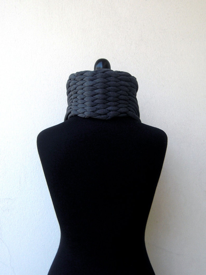 May include: A grey knitted infinity scarf on a black mannequin.