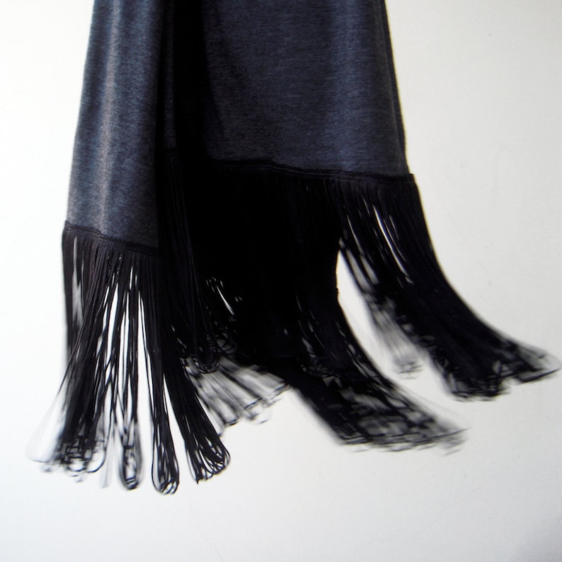 May include: A black fringed garment with a soft, textured fabric. The fringe is long and flowing, creating a dramatic effect.