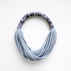 Peut inclure: Un collier en tissu bleu clair avec une bande &agrave; motifs gris fonc&eacute; et blanc.
