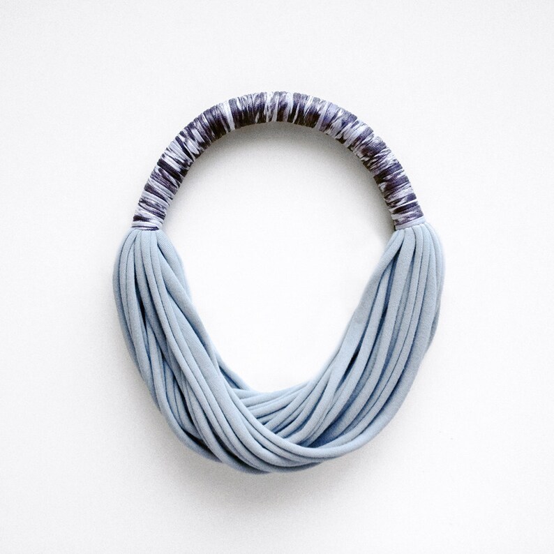 Peut inclure: Un collier en tissu bleu clair avec une bande &agrave; motifs gris fonc&eacute; et blanc.