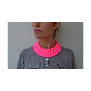 May include: A bright pink, multi-layered, braided choker necklace.