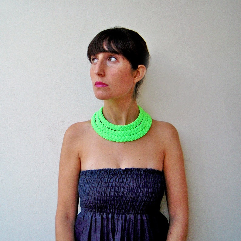 May include: A woman wearing a strapless black dress with a bright green layered necklace.