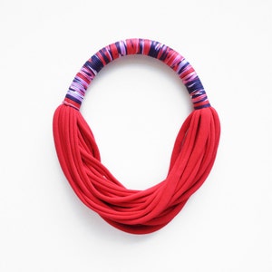 Peut inclure: Un collier en tissu rouge avec une bande ray&eacute;e multicolore autour du haut.