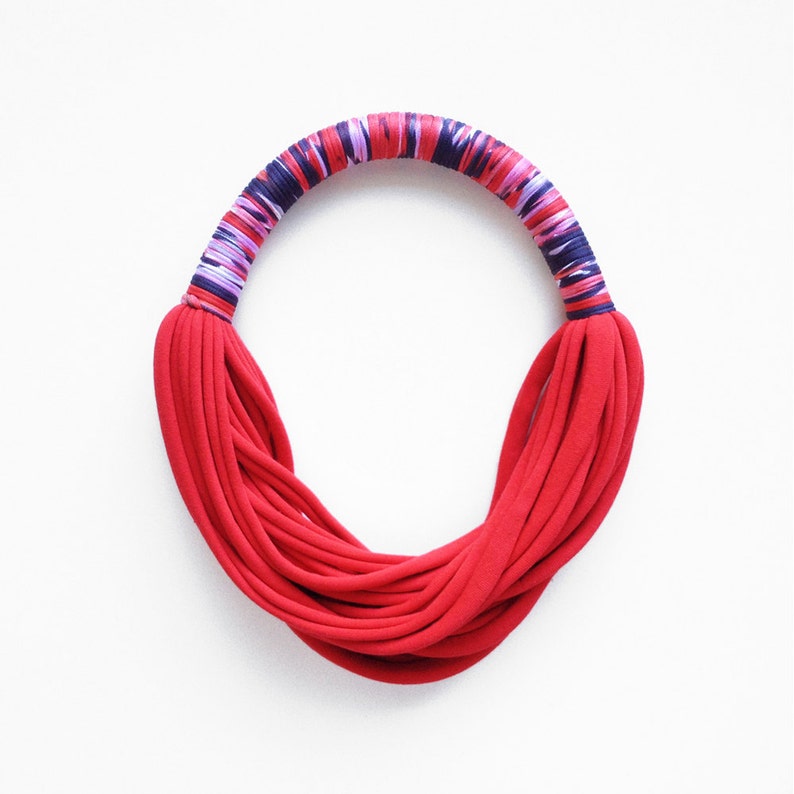 Peut inclure: Un collier en tissu rouge avec une bande ray&eacute;e multicolore autour du haut.