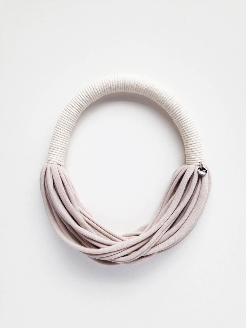 May include: A beige fabric necklace with a white rope detail and a small silver tag that says "MINA".