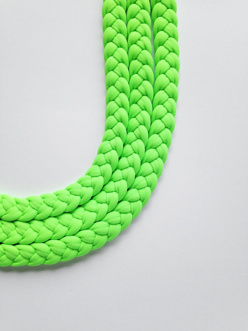 May include: A bright green braided rope made of soft fabric. The rope is thick and has a smooth texture.