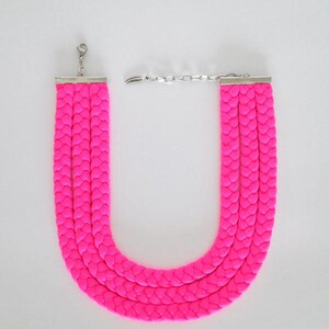 May include: A bright pink braided necklace with a silver clasp.