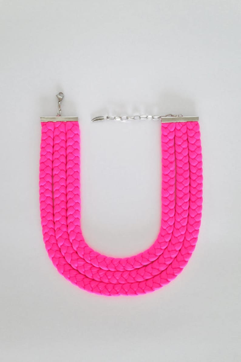May include: A bright pink braided necklace with a silver clasp.
