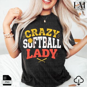 May include: Black t-shirt with the text "CRAZY SOFTBALL LADY" in yellow, white, and red. The design includes a softball, a baseball, and crossed bats. The shirt is a casual style.