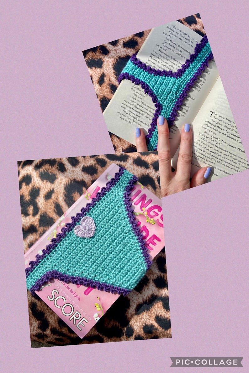 May include: A triangular crochet bookmark in bright teal with a dark purple scalloped border and a small, light purple crocheted heart accent in the center. The bookmark is shown placed on top of an open book with printed text.
