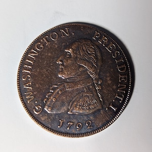 May include: A copper coin with a profile of George Washington and the text "G. WASHINGTON. PRESIDENT. 1792".
