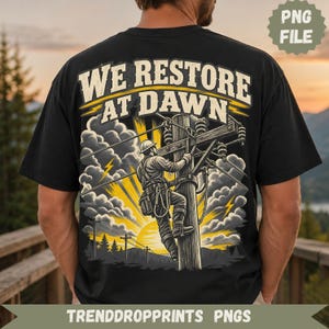 Puede incluir: Una camiseta negra con un gráfico en la espalda de un trabajador eléctrico subiendo a un poste de madera. El texto dice WE RESTORE AT DAWN. La ilustración incluye rayos de sol amarillos, nubes oscuras, relámpagos y una silueta de bosque.