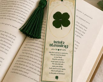 Può includere: Un segnalibro con un nappa verde, con un quadrifoglio e le parole "Irish Blessing". Il segnalibro è posto su un libro aperto, con testo visibile sulle pagine.