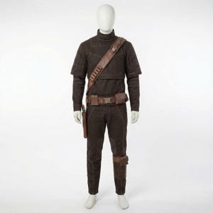 May include: A brown costume displayed on a mannequin. The outfit includes a long-sleeved top, pants, and a belt with pouches. A brown leather strap with bullet holders crosses the chest. A holster is attached to the leg. The costume is designed with visible stitching.
