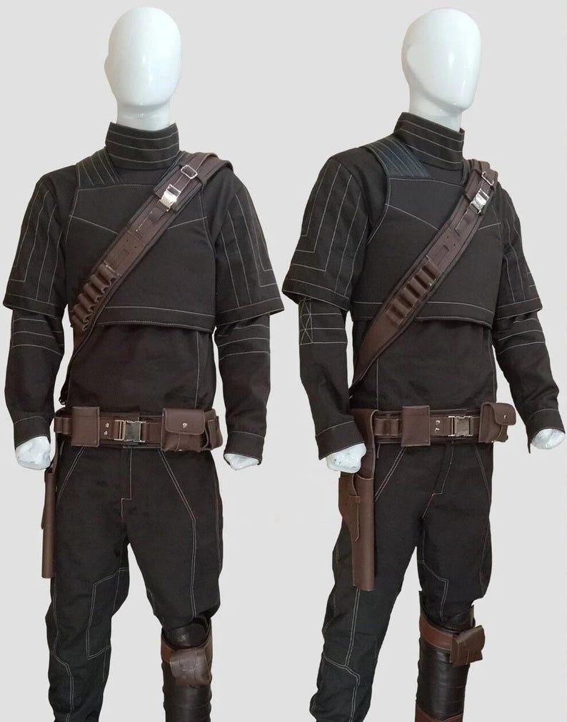 May include: Two complete black costumes with brown accents are displayed on mannequins. Each outfit includes a high-collared top, pants, a belt with pouches, and a shoulder strap. The costumes have white stitching details and brown holsters.