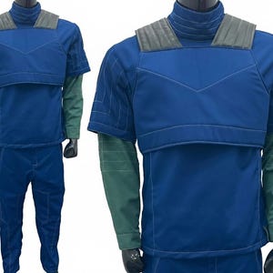 May include: A two-piece costume in shades of blue and green. The top is a short-sleeved, padded blue jacket with a high collar and gray shoulder accents. The long sleeves are green. The matching pants are blue.