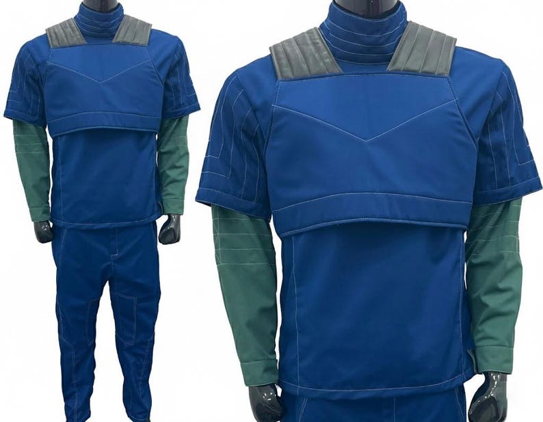 May include: A two-piece costume in shades of blue and green. The top is a short-sleeved, padded blue jacket with a high collar and gray shoulder accents. The long sleeves are green. The matching pants are blue.
