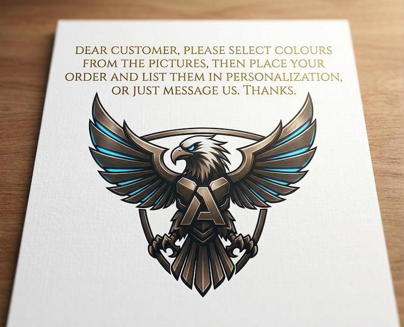 May include: A white card with a detailed illustration of an eagle with outstretched wings, in shades of brown, gray, and blue. The eagle is centered above a shield with the letter "A". Text at the top reads: "DEAR CUSTOMER, PLEASE SELECT COLOURS..."