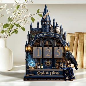 May include: A dark blue castle-shaped book tracker featuring the text "BOOKS READ THIS YEAR" and "Sophia's Library." The structure includes three numbered panels displaying 125, a glowing crystal ball, a black raven, and gold constellations.