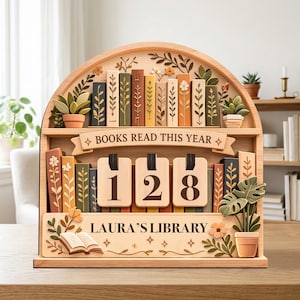 May include: Wooden bookshelf-shaped book counter with the text "BOOKS READ THIS YEAR" and "LAURA'S LIBRARY". The counter displays the number 128. The design includes miniature books, plants, and floral accents.