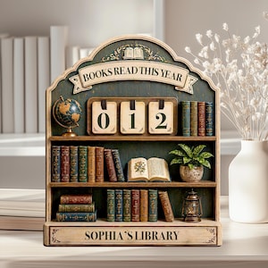 May include: Wooden bookshelf with the text "BOOKS READ THIS YEAR" and "SOPHIA'S LIBRARY". The shelf displays a globe, a plant, a lantern, and several miniature books. The counter reads "012".