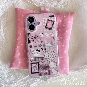 Op de afbeelding: Een roze telefoonhoesje met een doorzichtige rand, versierd met Hello Kitty-ontwerpen, harten, strikken en andere schattige afbeeldingen. De hoes ligt op een roze kussen met witte sterpatronen.