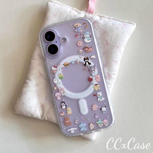 May include: A clear phone case with a lavender backing, adorned with colorful cartoon characters. The case features a circular design and a rectangular magnetic charging area. The text "CCxCase" is visible at the bottom right.