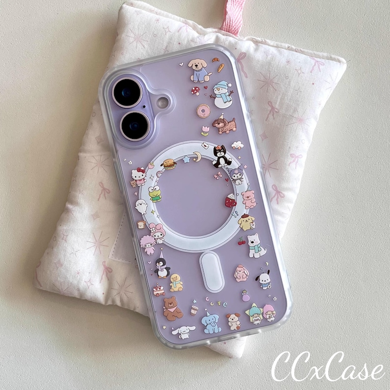 May include: A clear phone case with a lavender backing, adorned with colorful cartoon characters. The case features a circular design and a rectangular magnetic charging area. The text "CCxCase" is visible at the bottom right.