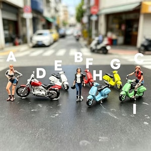 May include: Miniature figurines of women and motorcycles are arranged on a street. The motorcycles are in various colors, including red, white, yellow, and green. The women are dressed in casual attire.