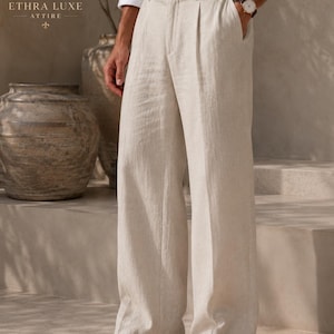 May include: Beige linen trousers featuring a high-waisted design with a single button closure, a front zipper fly, and deep pleats at the waist. These wide-leg pants have a relaxed fit, side pockets, and a clean, straight-leg silhouette.