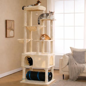 May include: A tall, multi-level beige cat tree featuring several carpeted platforms, two hanging fabric hammocks, a central enclosed cubby, and a black cylindrical tunnel at the base. Four cats of various colors are positioned on the structure.