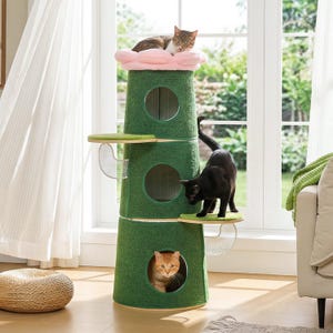 May include: A green cat tree with multiple levels, platforms, and a pink cloud-shaped bed. Three cats are interacting with the cat tree. One cat is resting on the top bed, one is exploring a platform, and another is inside a circular opening.