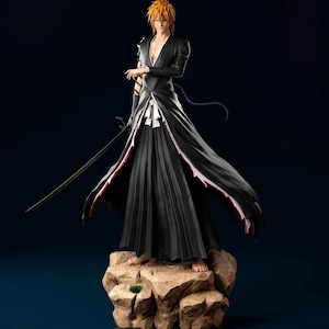 May include: A detailed figurine of a character with orange hair, wearing a long black coat with red trim, and holding a sword. The figure stands on a rocky base against a dark blue background.