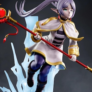 Può includere: Statuetta dettagliata di un personaggio femminile degli anime con lunghi capelli lavanda fluenti e orecchie a punta. Indossa un abito bianco e oro, tenendo in mano un bastone rosso con un grande globo rosso. La figura è posata dinamicamente, con una struttura blu simile al ghiaccio sotto.