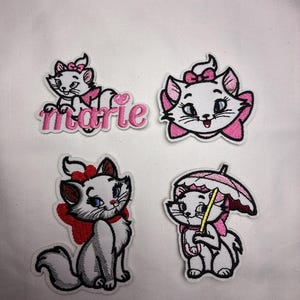 May include: Four embroidered patches featuring the character Marie from The Aristocats. The patches depict Marie in various poses, with pink bows and accents. One patch includes the name "marie" in pink script.