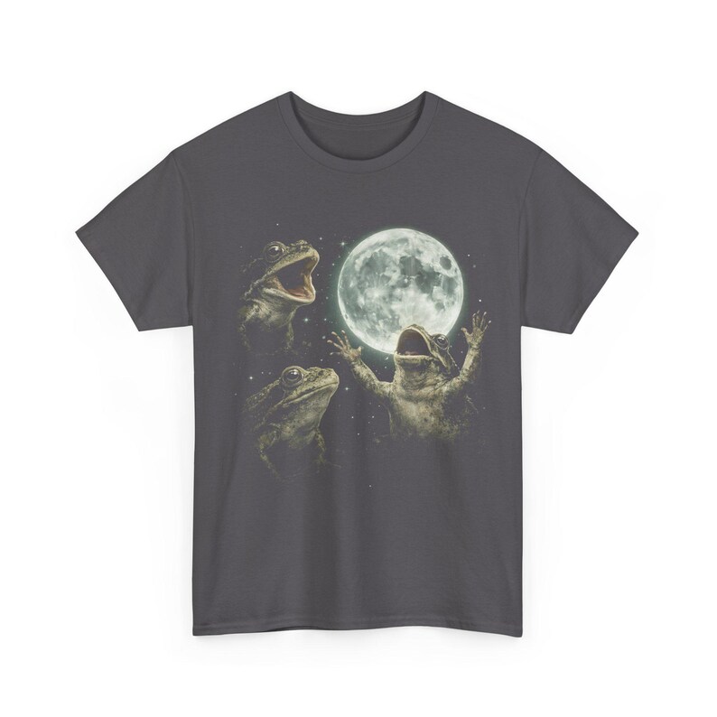 May include: Dark gray t-shirt featuring a whimsical design of three frogs with the moon in the background. The frogs appear to be singing or celebrating, with one frog raising its arms towards the moon. The design is detailed and artistic.