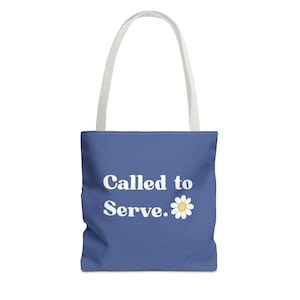 May include: A blue tote bag with white handles. The bag features the text "Called to Serve." in white, along with a white daisy graphic with a yellow center. The bag is designed for carrying items.