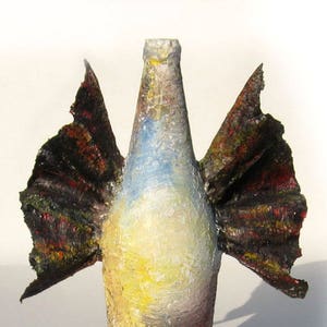 May include: A glass bottle with wings painted in shades of black, red, and yellow. The bottle is painted with a white, yellow, and blue sky scene. The bottle is a unique and creative art piece.