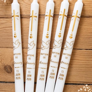 Peut inclure: Cinq bougies cierges blanches ornées d'un motif doré représentant une croix, des cœurs et une colombe. Le texte indique BAPTEME DE Amaury 13 JUIN 2026. Les bougies sont disposées verticalement, affichant un graphisme religieux et une date.