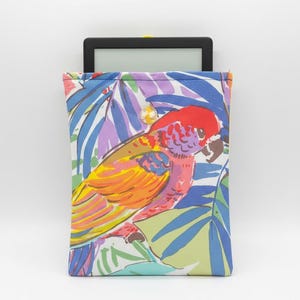Può includere: Una custodia colorata per e-reader con un vivace design di pappagallo tra foglie tropicali. La custodia presenta una miscela di colori vivaci, tra cui rosso, giallo, blu e viola. L'e-reader è parzialmente visibile.
