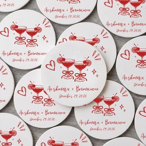 May include: A collection of round white coasters featuring a red graphic of two cocktail glasses with cherries and ribbons. Each coaster is printed with the text Aerkmax + Brmwiou and the date October 19.2026, accompanied by heart and star icons.