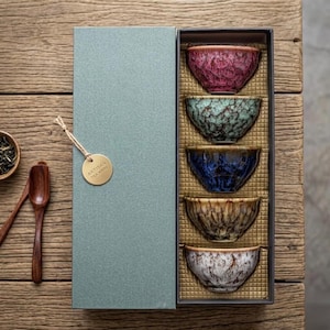 Peut inclure: Ensemble de trois tasses en céramique avec une finition mate et mouchetée. Les tasses sont de couleur crème, gris clair et gris foncé. Chaque tasse a un design simple et minimaliste avec une anse arrondie.