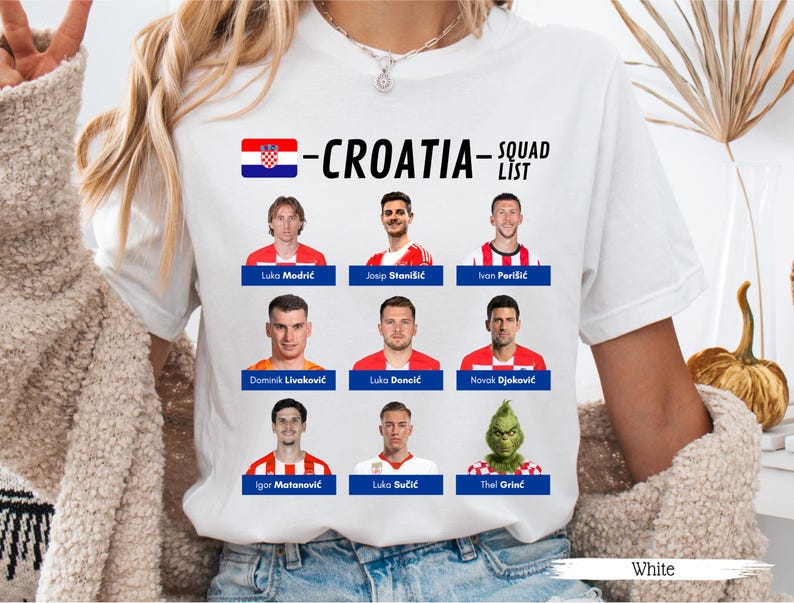 以下が含まれることがあります： クロアチアの国旗と「-CROATIA- SQUAD LIST」の文字が入った白いTシャツ。サッカー選手とグリンチの画像が表示されています。Tシャツの下部には「White」の文字があります。