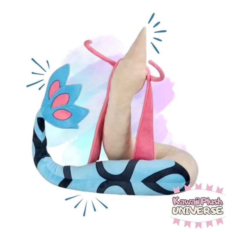 May include: A plush toy in the shape of a stylized creature, featuring a light blue body with black markings, a pink strap, and a beige head. The tail has blue and pink accents. The text "Kawaii Plush UNIVERSE" is visible.