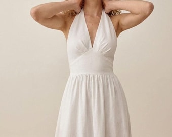 Vestido largo de lino blanco con escote halter, sin mangas, ideal para fiestas de verano en la playa.