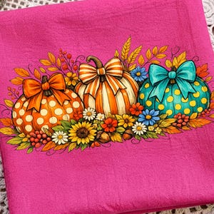 May include: A bright pink fabric featuring a central graphic of three pumpkins decorated with bows. The left pumpkin is orange with white polka dots, the center is orange and white striped, and the right is teal with yellow polka dots.